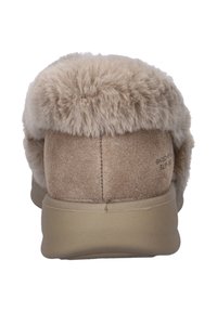 Beige pantoffel met een pluchen bontboord, zachte suède bovenkant en rubberen zool. Achteraanzicht toont de gestructureerde zool en het merlogo.