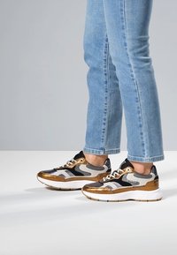 Sneakers met een kleurenpalet van zwart, wit en metallic goud. Voorzien van mesh en glanzende afwerking, ronde neus en vetersluiting. Casual ontwerp.