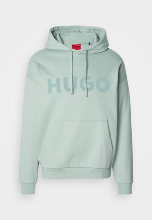 Svijetlozeleni pulover s kapuljačom, prednjim džepom u obliku kengura, i vezicom za kapuljaču, na kojem je ispisano "HUGO" velikim slovima na prsima.