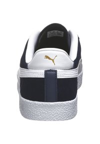 Zapatilla de ante azul marino con talón y suela blanca. Logo dorado de Puma en la parte trasera. Media suela blanca texturizada con una franja azul marino en contraste.