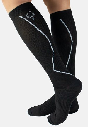 Knielange schwarze Kompressionssocken mit gerippter Textur, versehen mit einem weißen Akzentlinien-Design entlang der Seiten sowie verstärkten Fersen- und Zehenbereichen.