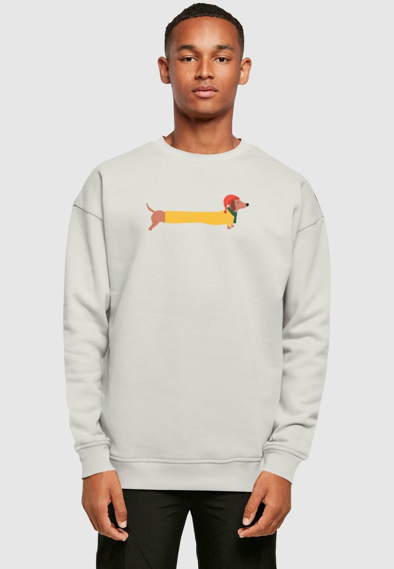 Lys grå sweatshirt med et tegneserie-design af en dachshund i gul, brun og rød. Lange ærmer og ribbede manchetter fuldender udseendet.