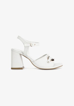 Białe sandały na obcasie z odkrytym palcem, regulowanym paskiem wokół kostki oraz dekoracyjną kokardką. Gładkie wykończenie z blokowym obcasem.