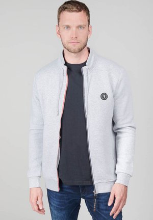 Light gray zip-up sweatshirt with a stand collar, featuring contrasting orange zipper detailing and a round logo patch on the chest.