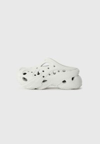 White clogs made from synthetic material, featuring a perforated design with multiple holes for ventilation and a curved, contoured shape.