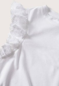 Witte T-shirt met een textuur van kant aan de linker schouder. De stof is zacht, met een gladde afwerking en een klassiek ronde hals ontwerp.