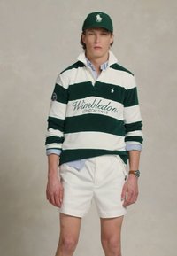 Tricou de rugby cu dungi albe și verzi, cu textul "Wimbledon LONDON SW19". Asortat cu pantaloni scurți albi. Accesoriile includ o șapcă verde și un ceas de mână.