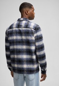 Karierte Hemd in Blau, Schwarz und Weiß. Hergestellt aus gewebtem Stoff mit einem strukturierten Design. Verfügt über einen Kragen und Knopfmanschetten. Legere Passform.