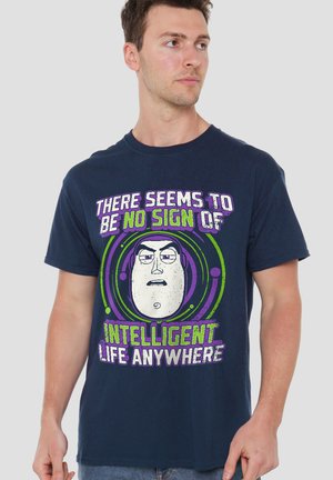 Man wearing navy blue T-shirt with cartoon face and text "There seems to be no sign of intelligent life anywhere" in green and purple.