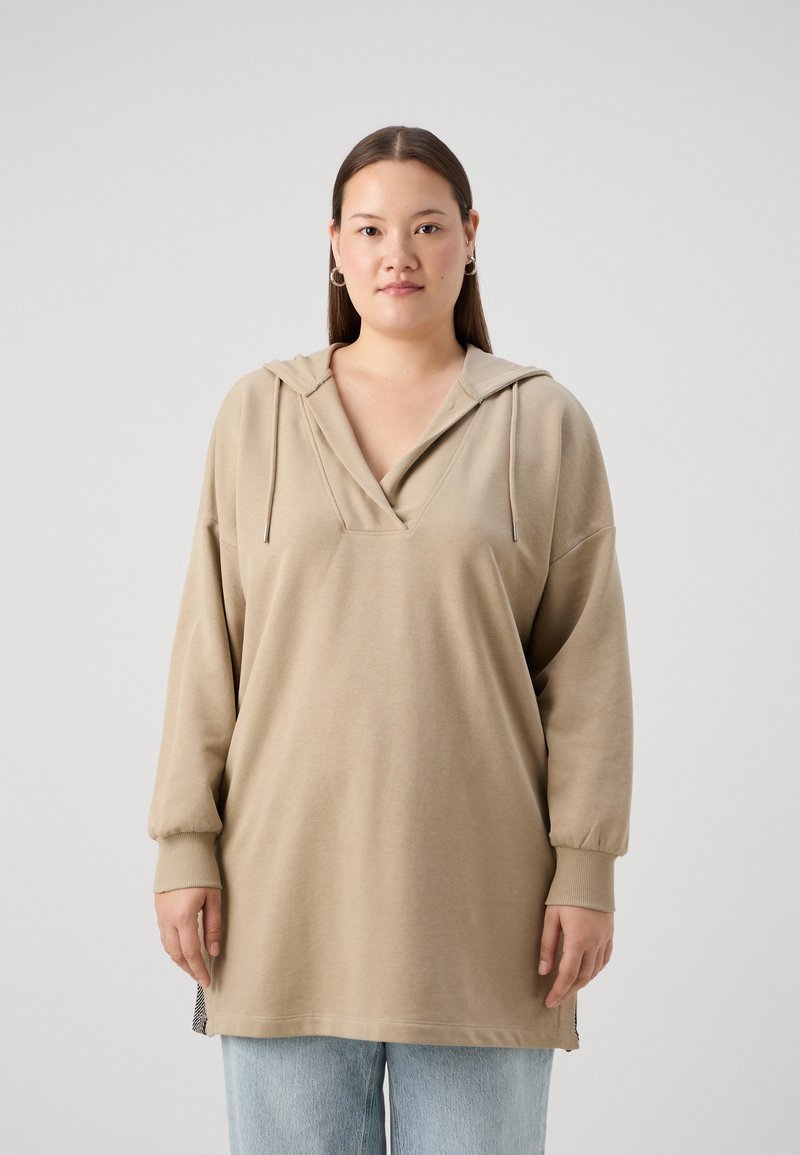 Lys beige oversized hettegenser med V-hals, snorhette og lange ermer. Har sidesplitter og et glatt, teksturert stoff.