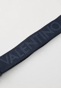 Sangle en textile bleu marine avec lettrage en relief portant l'inscription "VALENTINO." Le matériau a une texture lisse et un design plat.