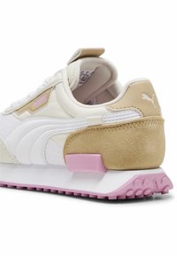 White sneaker with beige suede accents, featuring a pink rubber heel section, textured mesh fabric, and Puma branding on the side.