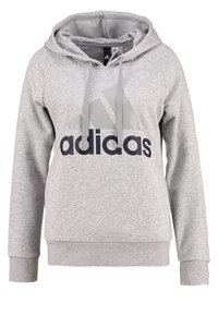 Sudadera gris de algodón con bolsillo tipo canguro en la parte delantera. Presenta un gran logo negro de "adidas" y un gráfico triangular gris en el pecho.