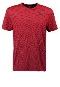 Camiseta deportiva roja de manga corta, con cuello redondo, tejido texturizado y un sutil patrón diagonal. Presenta un logo negro de Nike en el pecho.