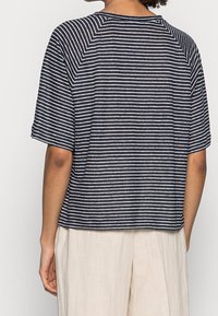Blusa de manga corta a rayas marinas con mangas anchas y un ajuste relajado, que presenta rayas horizontales blancas y un escote redondeado.