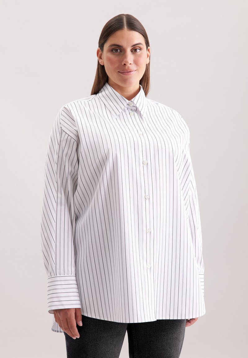 Camicia bianca con righe verticali blu navy, dotata di colletto appuntito e maniche lunghe con polsini larghi. Tessuto morbido con una superficie liscia.