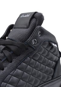 Czarne sneakersy typu high-top z pikowaną teksturą, wykonane z materiału skórzanego i czarnymi sznurówkami. Charakteryzują się markowym językiem i oczkami.