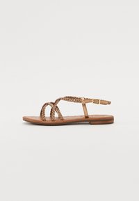 Sandales tressées marron avec semelle plate, dotées d'une sangle avec une boucle et d'une semelle intérieure texturée. Design élégant et minimal pour les températures chaudes.