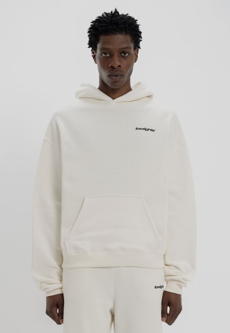 Κρεμ χρώματος φούτερ από μαλακό ύφασμα, με μπροστινή τσέπη και μαύρο λογότυπο στο στήθος. Χαλαρή εφαρμογή με κουκούλα που έχει κορδόνι.