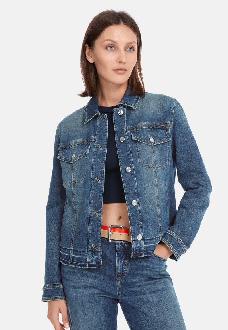 Denim jacket in medium blue with a collared neckline, button closure, and two chest pockets; features stitching accents and a relaxed fit.