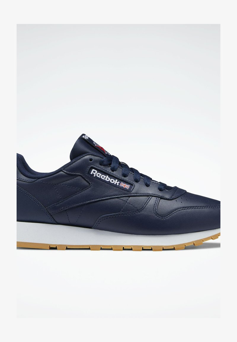 Jūras zila ādas sporta apavi ar baltu un gumijas zoli, ar mežģīņu aizdari, Reebok zīmolu un izsmalcinātu dizainu.