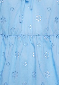Jasnoniebieska bawełniana tkanina z haftowanymi wzorami kwiatów i wycięciami; talia marszczona z ozdobną tasiemką.