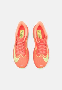 Neonoranssit juoksukengät, joissa on verkkomateriaali, kontrastiväriset keltaiset yksityiskohdat, litteät nauhat ja pehmustetut pohjat; suunniteltu suorituskykyyn ja mukavuuteen.