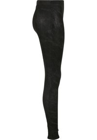 Leggings noirs taille haute et coupe slim avec une texture subtile imitant le daim, vus de côté sur fond blanc.