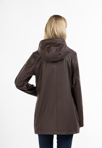 Giacca impermeabile marrone con cappuccio, texture liscia, design a lunghezza intermedia, con taglio dritto e dettagli minimi sulle maniche.