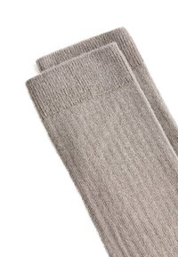 Pair of folded light gray ribbed knit socks on a white background, showing texture and cuff detail.