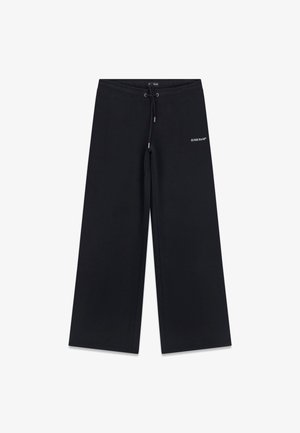 Czarne szerokie spodnie dresowe z elastycznym paskiem i sznurkiem oraz małym białym logo "GUESS JEANS" na górnej części lewego uda.