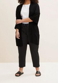 Czarna, lekka kimono z trzema ćwierć rękawami, zestawiona z białym t-shirtem i czarnymi spodniami z troczkiem, do tego płaskie czarne sandały.