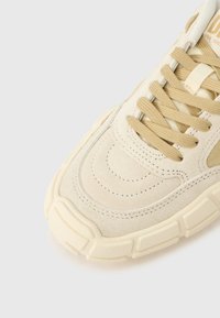 Αθλητικό παπούτσι με αν ώτερο μέρος από βελούδινο σουέτ σε κρεμ απόχρωση, μπεζ κορδόνια και υφή στη λαστιχένια σόλα. Διαθέτει ραμμένες λεπτομέρειες και στρογγυλή σχεδίαση μύτης.