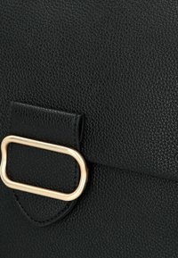 Borsa a tracolla in pelle nera texturizzata con un'accattivante fibbia in metallo dorato e chiusura a patta liscia. Focus sugli elementi di design pratici.