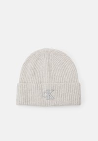 Gorro de punto acanalado de color beige claro con un dobladillo, bordado con un pequeño logo "cK" en gris en el centro frontal.