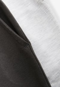 Bomuldsstof i mørkegrå og lysegrå farver med en glat tekstur, synlige syninger langs kanterne og en diskret farveovergang.