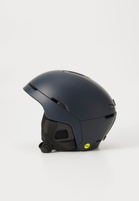 Granatowy kask narciarski o opływowym, matowym wykończeniu. Wyposażony w oznaczenie MIPS, regulowany pasek, otwory wentylacyjne oraz elegancki, zaokrąglony kształt.