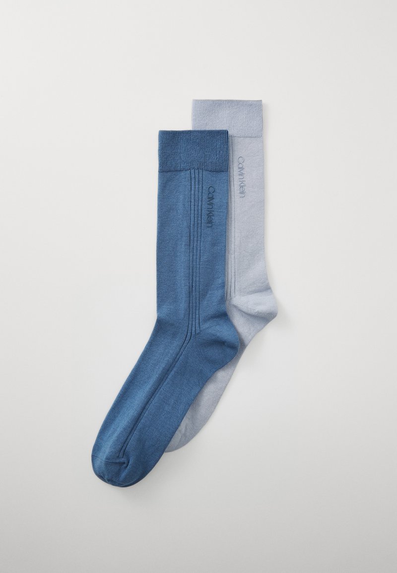 Due coppie di calzini: una blu scuro e una azzurro chiaro. Entrambe hanno una texture liscia e lavorata a maglia e presentano il logo "Calvin Klein" di lato.