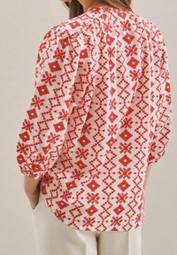 Hedvábná blůza s červeno-bílým vzorem a nafouknutými rukávy, s geometrickými designy, lehkým materiálem a volným střihem.