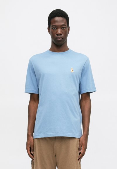 Ανοιχτό μπλε βαμβακερό μπλουζάκι με στρογγυλή λαιμόκοψη και κοντά μανίκια, με ένα μικρό κέντημα σε κίτρινο χρώμα μιας αλεπούς στο αριστερό στήθος.