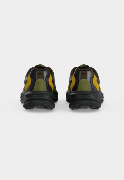 Paire de chaussures de sport multicolores vues de dos, avec semelles noires et panneaux supérieurs jaunes, verts et foncés.