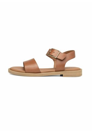 Brązowa skórzana płaska sandałka z paskiem na kostce i metalową klamrą, otwarty przód i beżowa podeszwa, przedstawiona na białym tle.