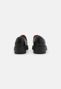 Schwarze Lederhalbschuhe mit abgerundeten Zehen, glatter Oberfläche, niedrigem Blockabsatz und gestickten Details an der Rückseite.
