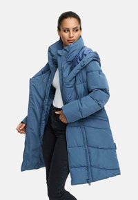 Long blue puffer coat with a high neck, featuring a zipper and button closure, quilted pattern, and a detachable hood.