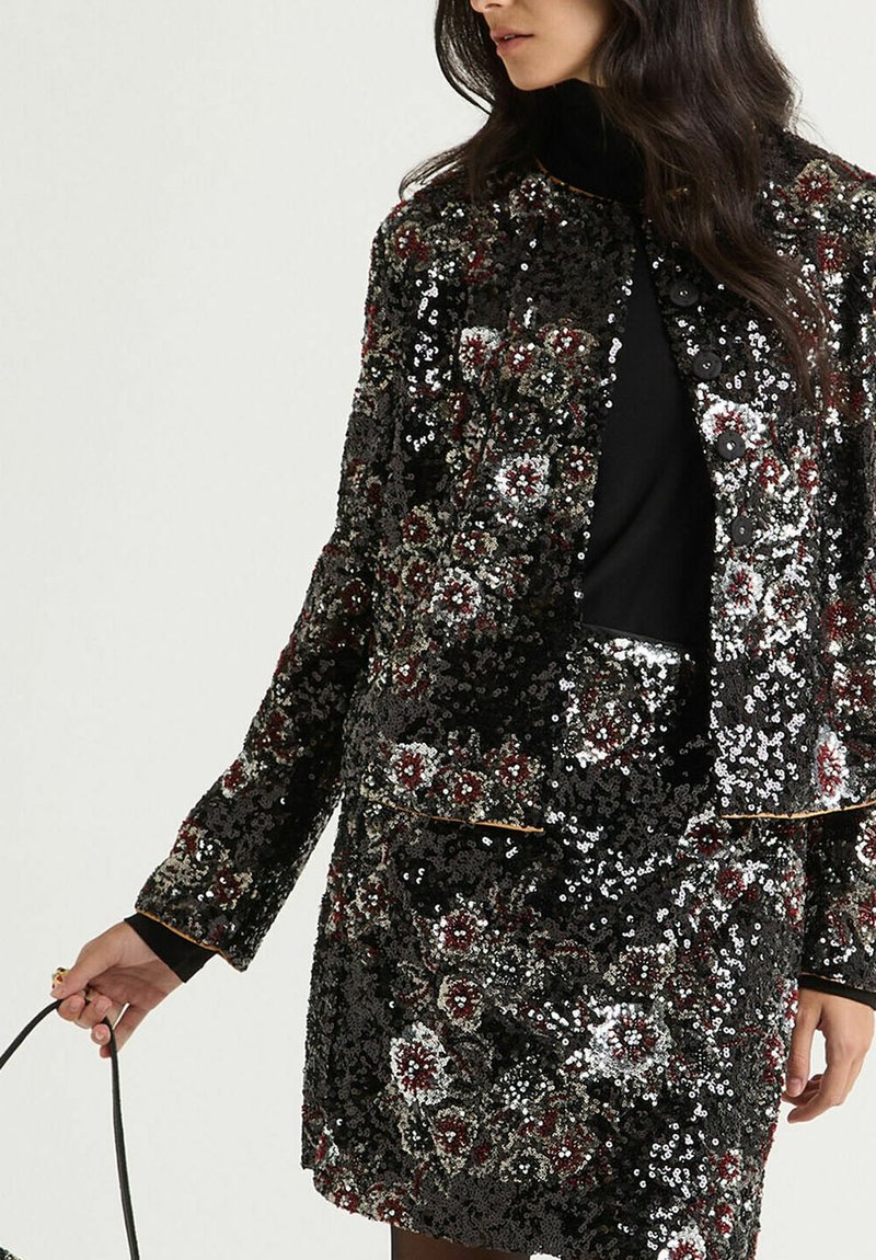 Veste à sequins avec motif floral dans des tons de noir, argent et bordeaux. Dotée d'une coupe structurée et de fermetures à boutons, surface texturée.