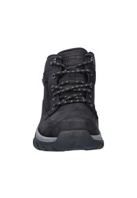 Zwarte waterdichte wandelschoenen hebben een glad leren bovenwerk, ronde veter met reflecterende accenten en een gestructureerde rubberen zool.