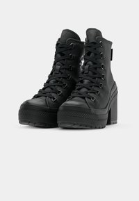 Bottes de cheville à plateforme noires en cuir texturé, avec un bout rond, un laçage sur le devant et un patch logo sur le côté. Talon bloc épais.