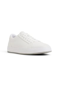 Zapatillas blancas que presentan una parte superior de cuero suave, punta redonda y una suela de goma plana con un diseño minimalista. Los cordones son claramente visibles.
