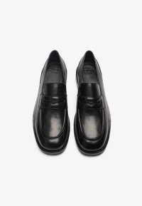 Zwarte leren instapschoenen met een gladde afwerking, voorzien van een ronde neus, verhoogde gestikte accenten en een platte rubberen zool.