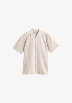 Polo shirt bej cu mânecă scurtă, cu fermoar frontal, având dungi verticale texturate și un guler neted. Fabricat din material moale.